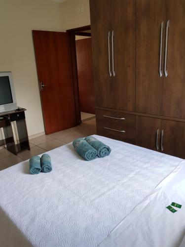 a white bed with two blue pillows on it at Casa da Cachoeira in Brotas