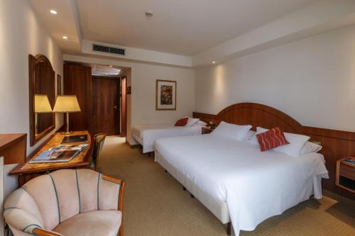 a hotel room with two beds and a chair at Hotel Terme Millepini in Montegrotto Terme