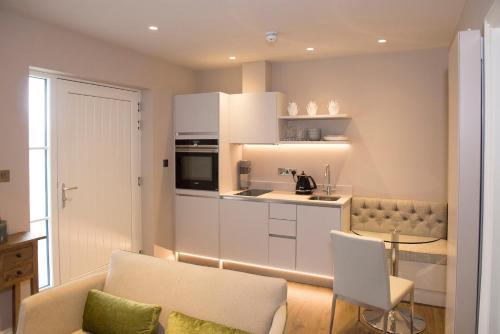 a living room with a couch and a kitchen at Roundthorn Country House & Luxury Apartments in Penrith