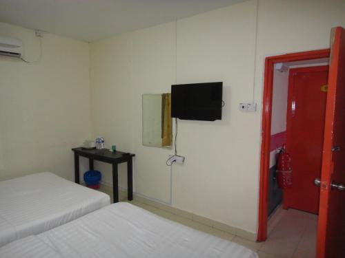 a room with two beds and a tv on the wall at Hotel Ocean in Lahad Datu
