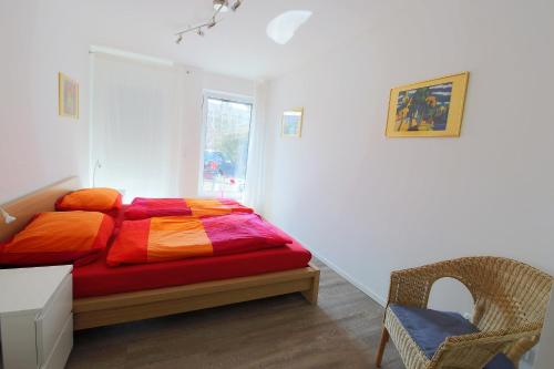1 dormitorio con 1 cama con sábanas coloridas y silla en City Apartment - Lüneburg Am Schierbrunnen, en Lüneburg