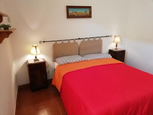 a bedroom with a red bed and two lamps at Appartamento Il Pianetto in Celle sul Rigo