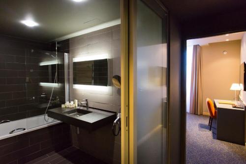 a bathroom with a sink and a mirror at Hôtel du Morvan in Luzy