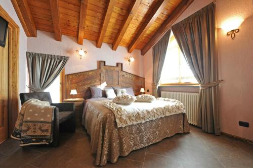a bedroom with a large bed and a chair at Gresil Residence in Champoluc