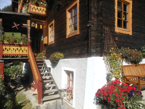 a wooden house with flowers and a stairway at Apartments Obergraferhof in Innervillgraten
