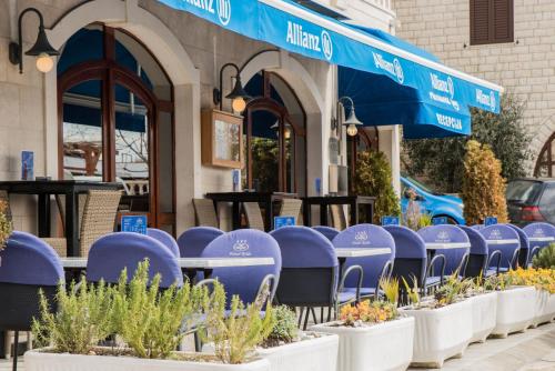 a row of purple chairs and plants outside a restaurant at Hotel Krilo in Podstrana