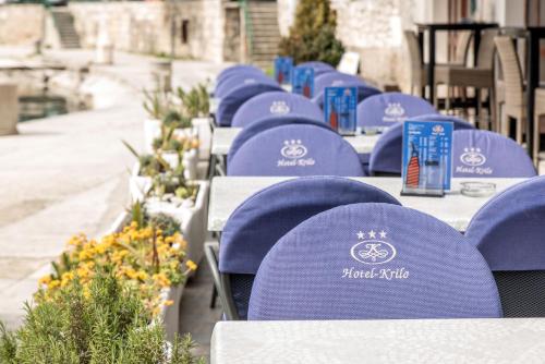 a row of tables with blue chairs and flowers at Hotel Krilo in Podstrana