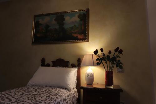 a bedroom with a bed with a vase of flowers and a lamp at Platea Oche in Sutri