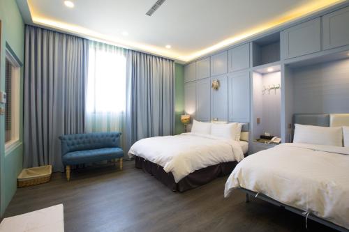 a hotel room with two beds and a blue chair at Puli Story House in Puli