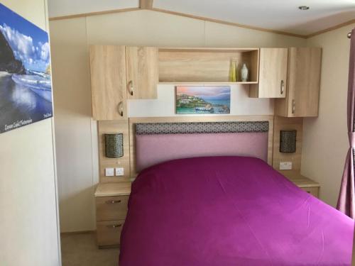 małą sypialnię z fioletowym łóżkiem w przyczepie kempingowej w obiekcie Newquay Valley View w Newquay