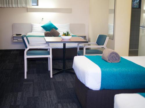 a room with two beds and a table and chairs at Sunnybank Star Hotel in Brisbane