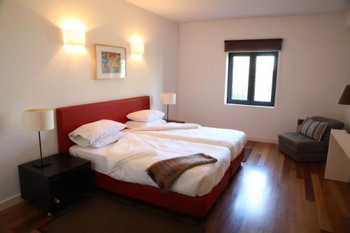 a bedroom with a large bed with a red headboard at Casa dos Arcos in Caramulo