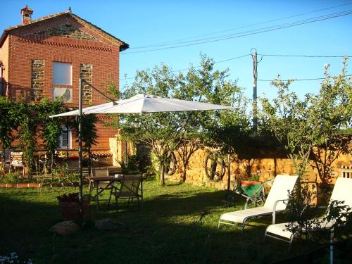 a patio with a table and chairs and an umbrella at Hotel Rural La Rosa de los Tiempos in Carneros