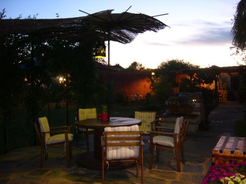 a patio with a table and chairs and an umbrella at Hotel Rural La Rosa de los Tiempos in Carneros