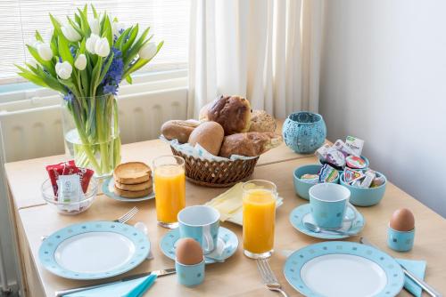 einen Tisch mit Tellern und Eiern sowie einen Korb mit Brot in der Unterkunft de Vloedlijn in Callantsoog