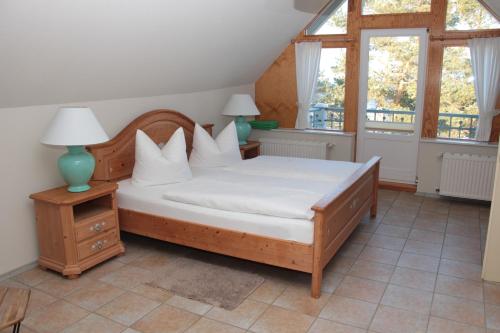una camera da letto con letto, lenzuola e cuscini bianchi di Pension auf der Düne a Heringsdorf