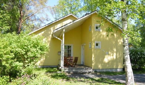 a white house with a wooden roof and trees at Nallikari Holiday Village Cottages in Oulu