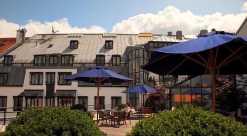 a patio table with umbrellas in front of a building at Hotel München Palace in Munich