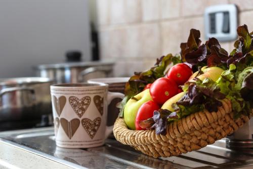 a basket of fruits and vegetables on a counter with two cups at Residence Mediterraneo in Marina di Grosseto