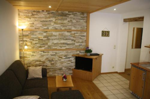 a living room with a couch and a brick wall at Pension Schusterpeter in Bad Tölz