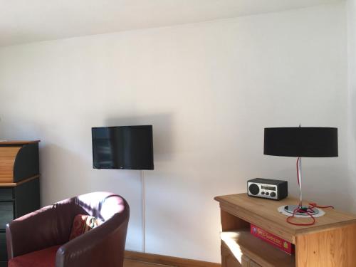 a living room with a chair and a tv on a wall at Ferienwohnung Sachrang in Sachrang