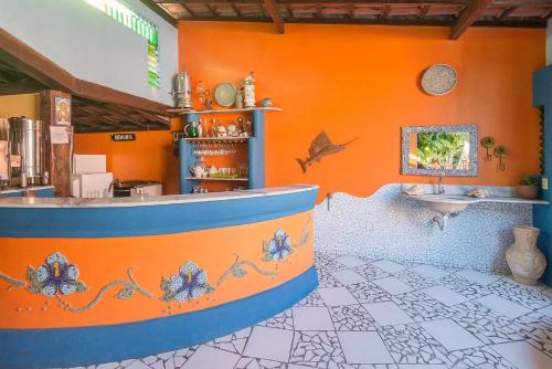 baño con pared de color naranja y lavamanos en Pousada Bemvirá, en Arraial d'Ajuda