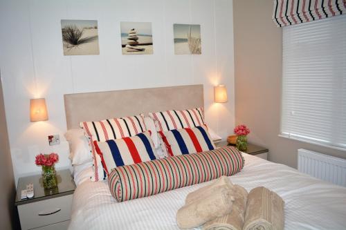 a bedroom with a white bed with two striped pillows at Ein Yfory in Benllech