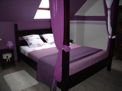 Un dormitorio con una cama con sábanas moradas y una ventana en au clair de lune, en Mehun-sur-Yèvre