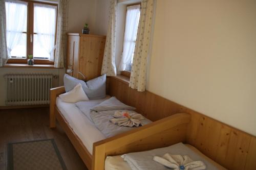 a small room with a bed with two windows at Pension Schusterpeter in Bad Tölz