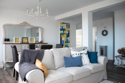 a living room with a white couch and blue pillows at Apartamento Turístico Alfredo Truan in Gijón