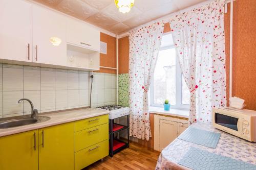 布祖盧克的住宿－Microrayon 2 Dom 8，厨房配有黄色橱柜和带微波炉的窗户。