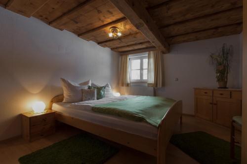 ein Schlafzimmer mit einem Bett mit einer grünen Bettdecke und einem Fenster in der Unterkunft Ferienwohnung Rehkoglgut in Bad Goisern