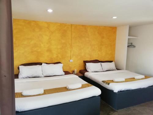 two beds in a room with yellow walls at Wanlapa Farmstay in Ban Khok Krathiam