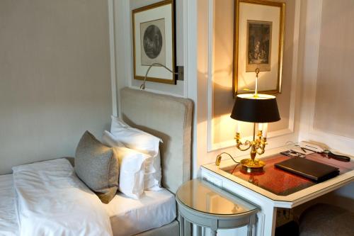 a bedroom with a bed and a table with a lamp at Hotel München Palace in Munich