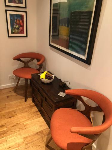 a living room with two chairs and a bowl of fruit at Romantic Bungalow in Notting Hill in London