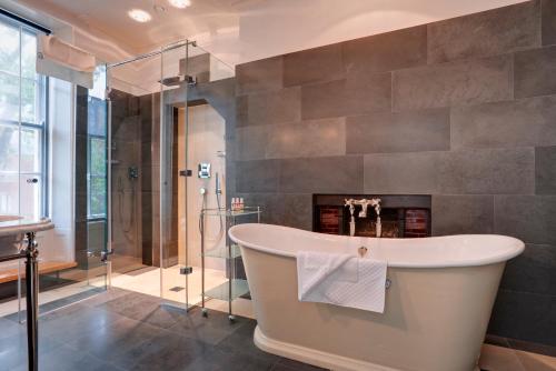 a bath tub in a bathroom with a fireplace at Southernhay House Hotel in Exeter