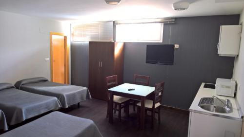 a room with two beds and a table and a sink at Hostal T4 in Paracuellos de Jarama