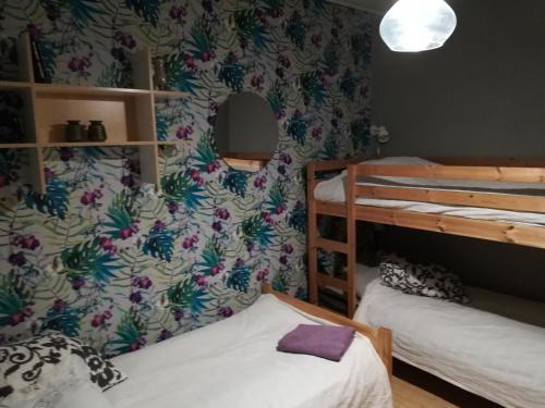 a room with two bunk beds and a wall with floral wallpaper at Vekhyttegården in Fjugesta