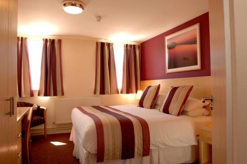 a hotel room with a large bed with red walls at Royal Maritime Hotel in Portsmouth