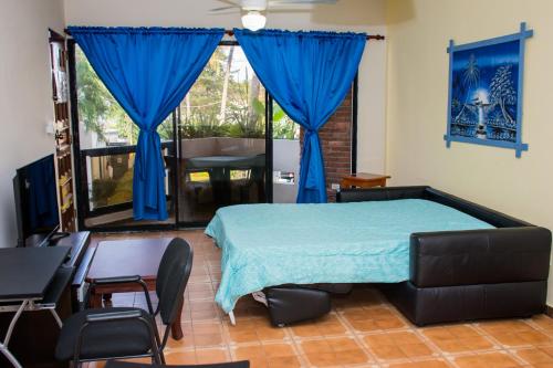 1 dormitorio con 1 cama con cortinas azules y escritorio en Apartment Costambar Puerto Plata, en San Felipe de Puerto Plata