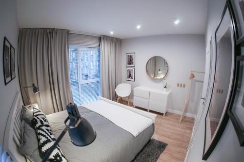 Dormitorio pequeño con cama y espejo en Barson Apartments, en Varsovia