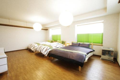 a bedroom with two beds and a large window at AKKO's Guest House in Sapporo