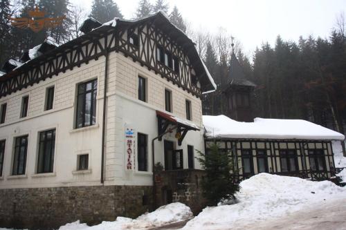 uma grande casa branca com neve em frente em Hotel Stavilar em Sinaia