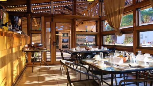 a restaurant with tables and chairs in a room with windows at Hotel La Cochera in San Pedro de Atacama