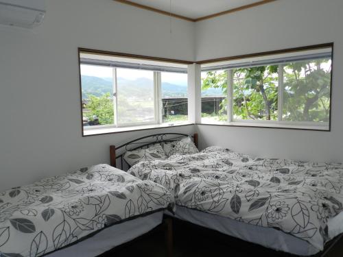 1 dormitorio con 2 camas y 2 ventanas en B&B Toyonoakari, en Taragi