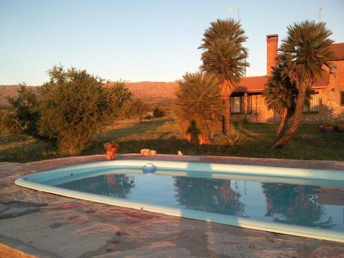 a swimming pool in front of a house with palm trees at La Palmita in Papagayos