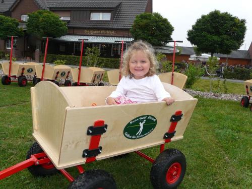 a little girl is sitting in a wooden wagon at Gasthaus Eickholt GmbH in Ascheberg