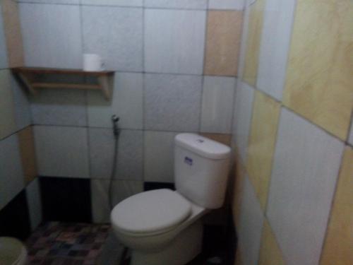 a bathroom with a white toilet in a room at Susan Homestay in Batukaras