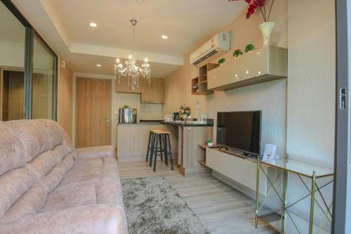a living room with a couch and a kitchen at The Rain Cha Am by Paka in Cha Am