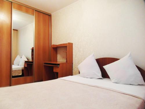 トムスクにあるКварт отель Надежда Базарный 12のベッドルーム1室(白い枕と鏡付きのベッド1台付)